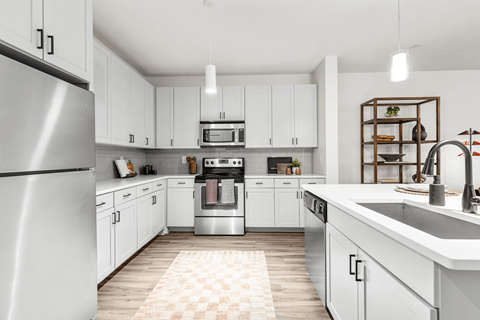 A modern kitchen with white cabinets and a checkered rug on the floor.