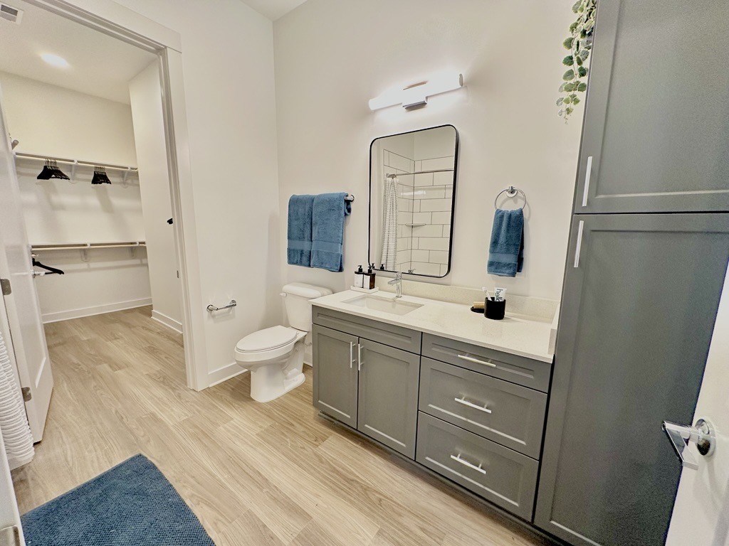 A bathroom with a toilet, sink, and mirror.