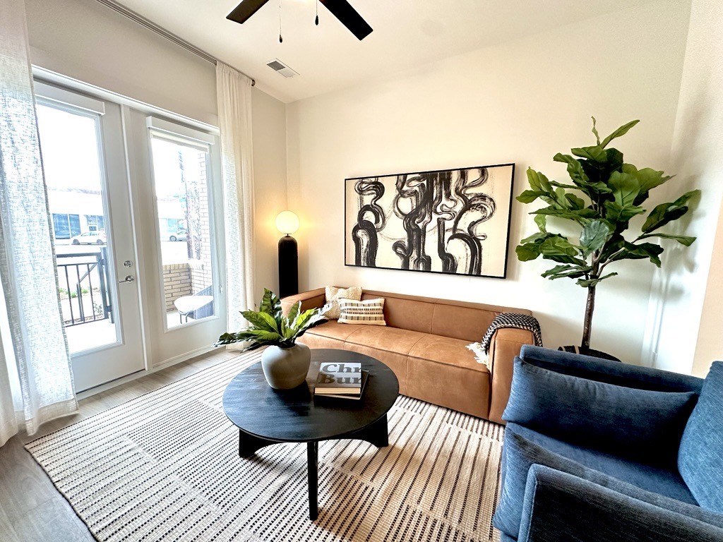 A living room with a brown couch, a black coffee table, and a large abstract painting on the wall.