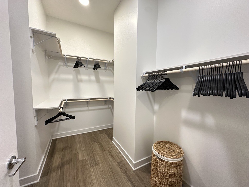 A walk in closet with clothes hanging on hangers.