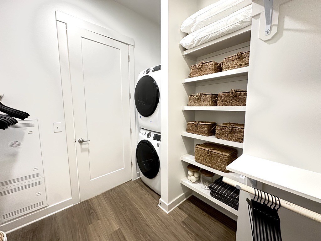 A white laundry room with a washer and dryer and a shelf with baskets.