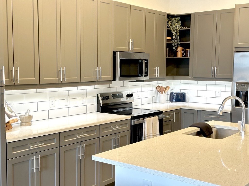 A kitchen with a white counter top and beige cabinets.