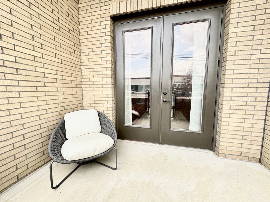 A chair with a white cushion sits in front of a glass door.