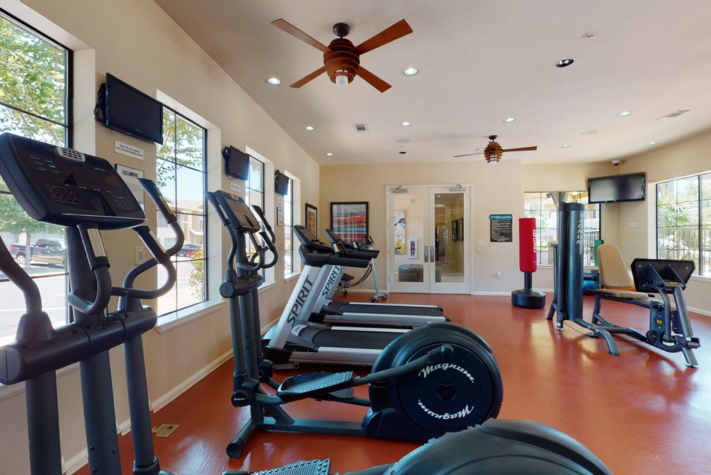 a gym with cardio equipment and a ceiling fan