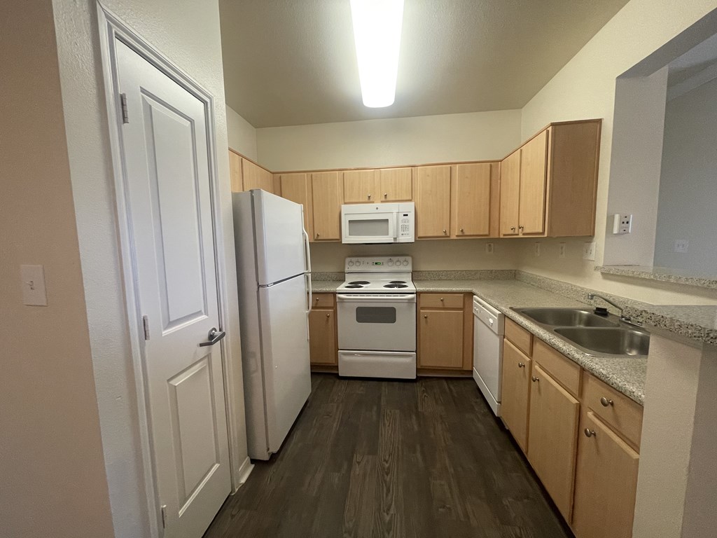 A kitchen with a white refrigerator, white oven, and wooden cabinets.
