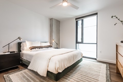 A bedroom with a large bed and a ceiling fan.