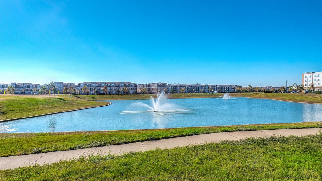 a fountain in a pond with a city in the background