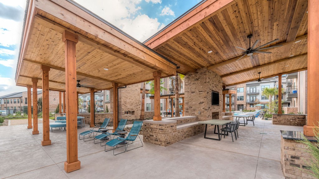 a covered patio with tables and chairs and a brick fireplace