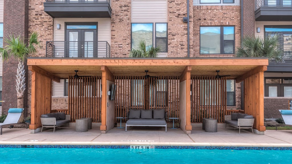 a covered patio with chairs next to a swimming pool