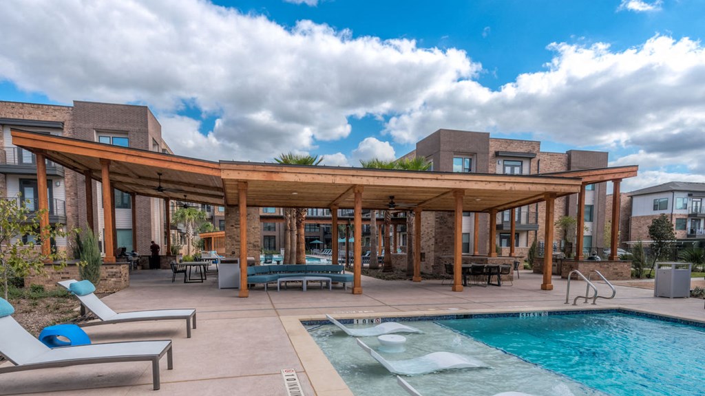 a swimming pool with a patio and a building in the background
