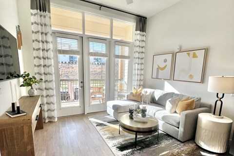A living room with a grey couch, a coffee table, and a painting on the wall.