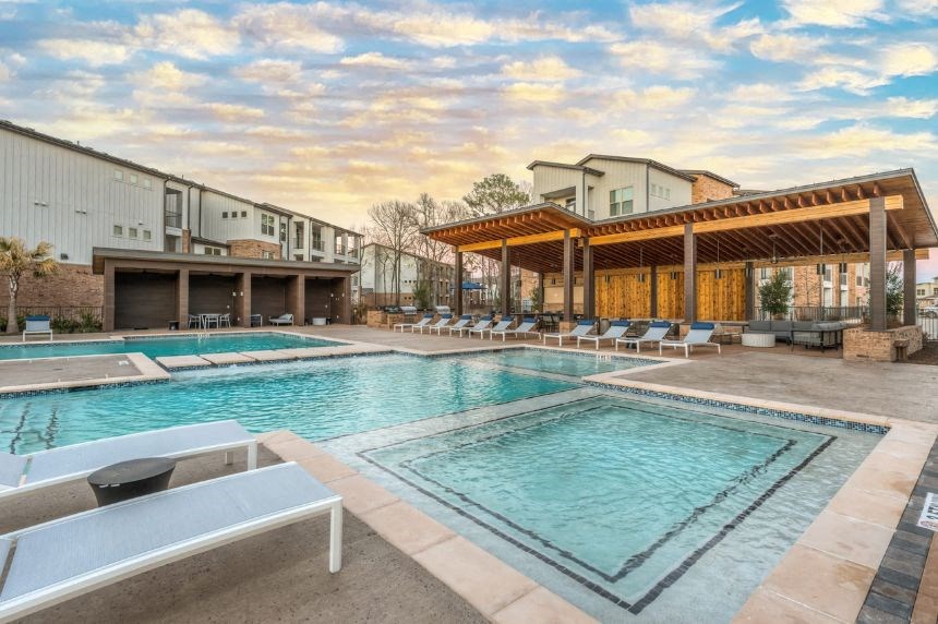 a resort style pool with lounge chairs and a pavilion