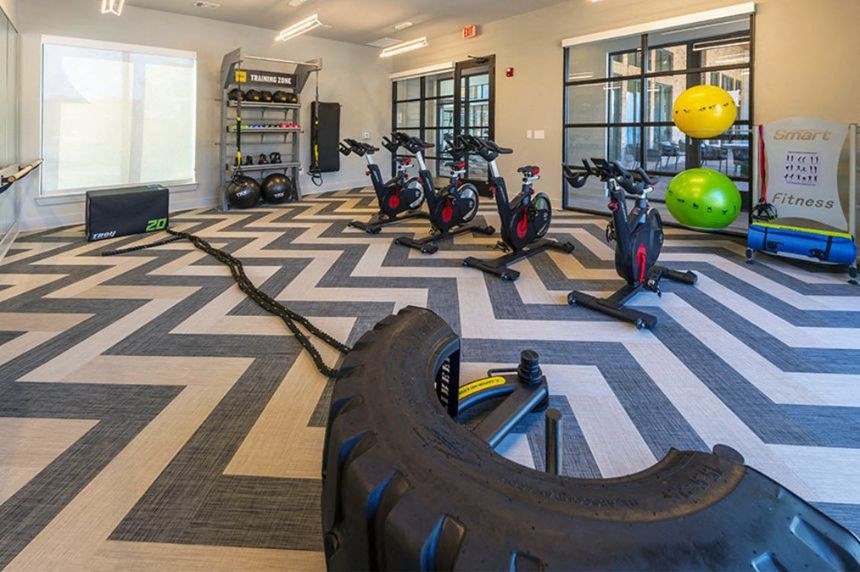 a gym with several bikes and a tire on the floor