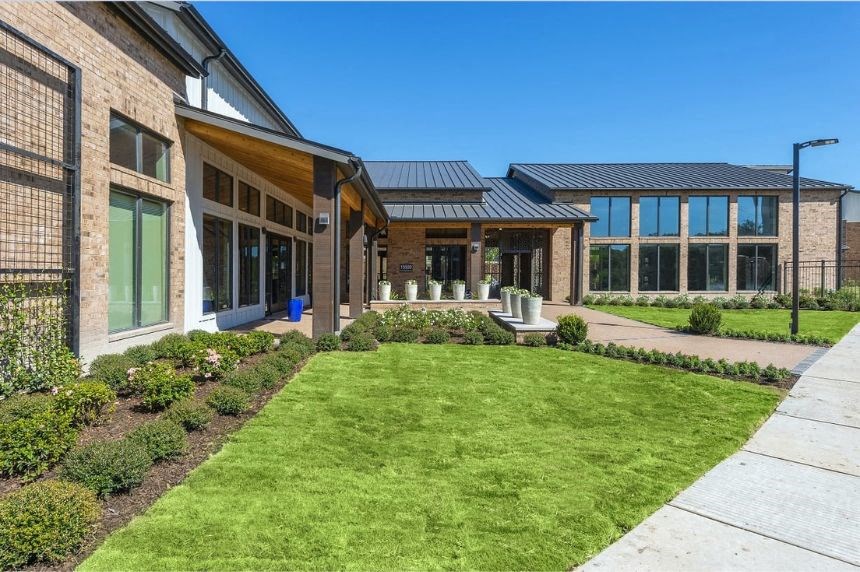 the front of a building with a lawn and a sidewalk