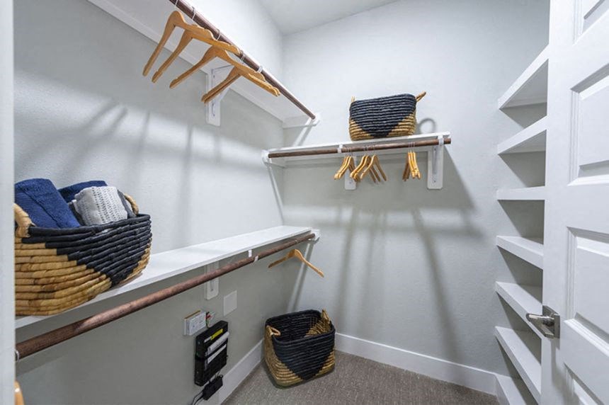 a walk in closet with baskets and shelves