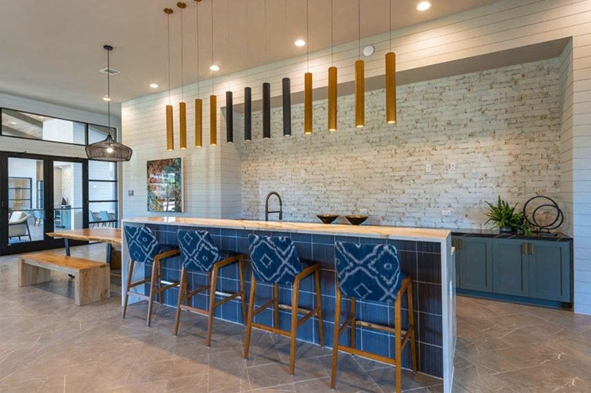 a kitchen with blue bar stools and a brick wall