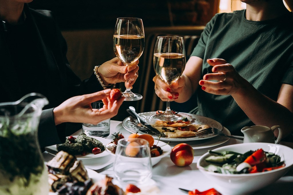 people sitting at a table with food and wine glasses