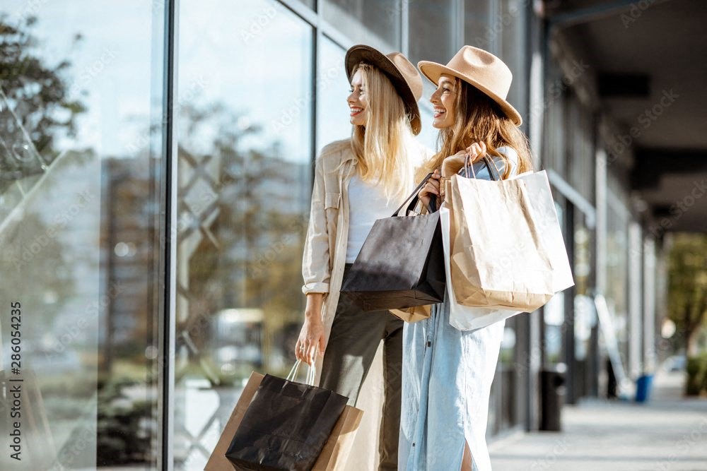 two women walking down the street with shopping bags