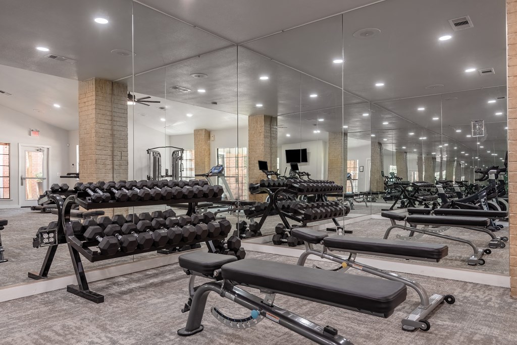 a gym with weights and cardio equipment in a building with mirrored walls