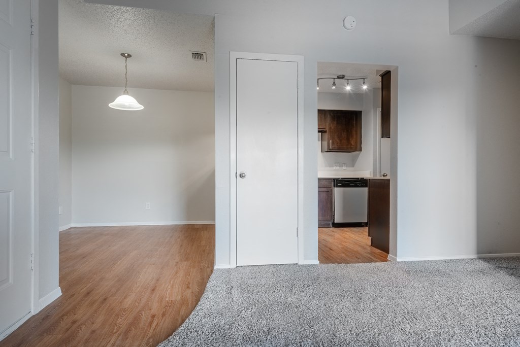 an empty living room with a door to a kitchen