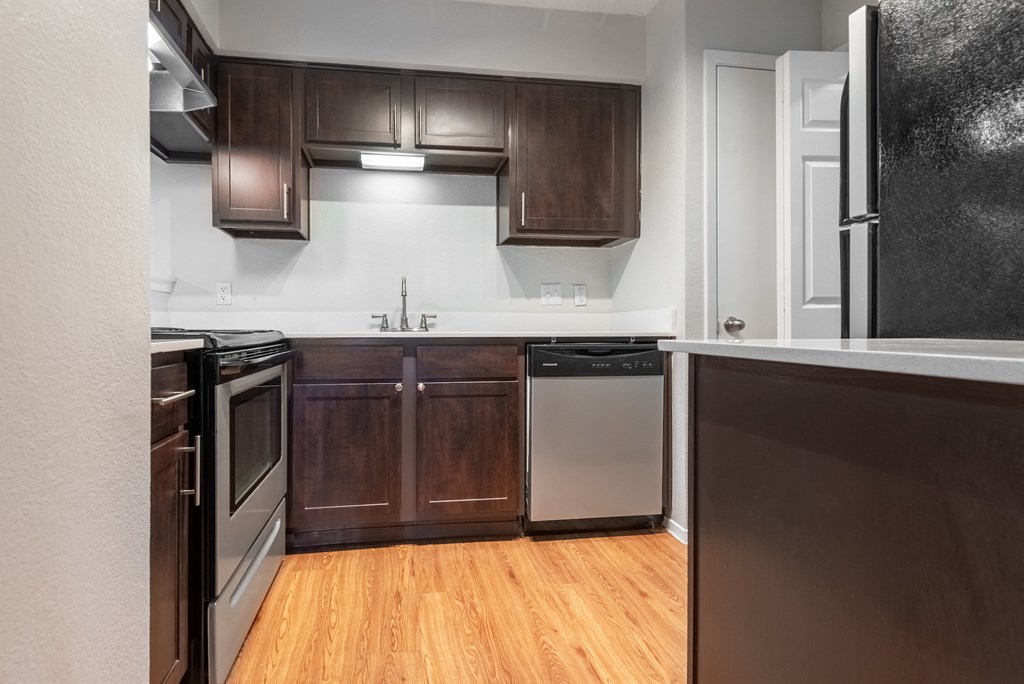 an empty kitchen with wooden cabinets and stainless steel appliances