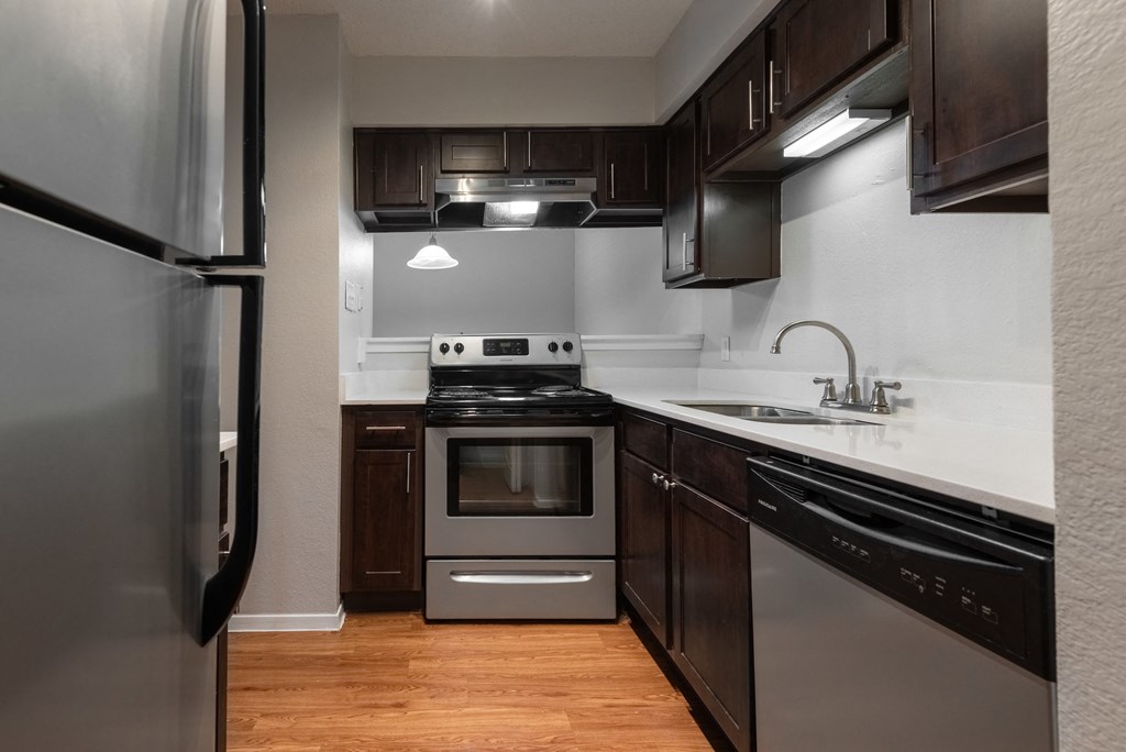 an empty kitchen with stainless steel appliances and dark wood cabinets