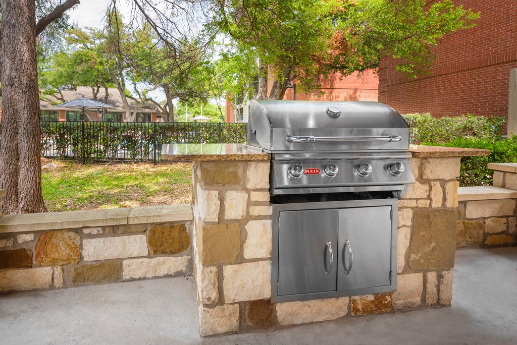 an outdoor kitchen with a stone wall and a granite countertop
