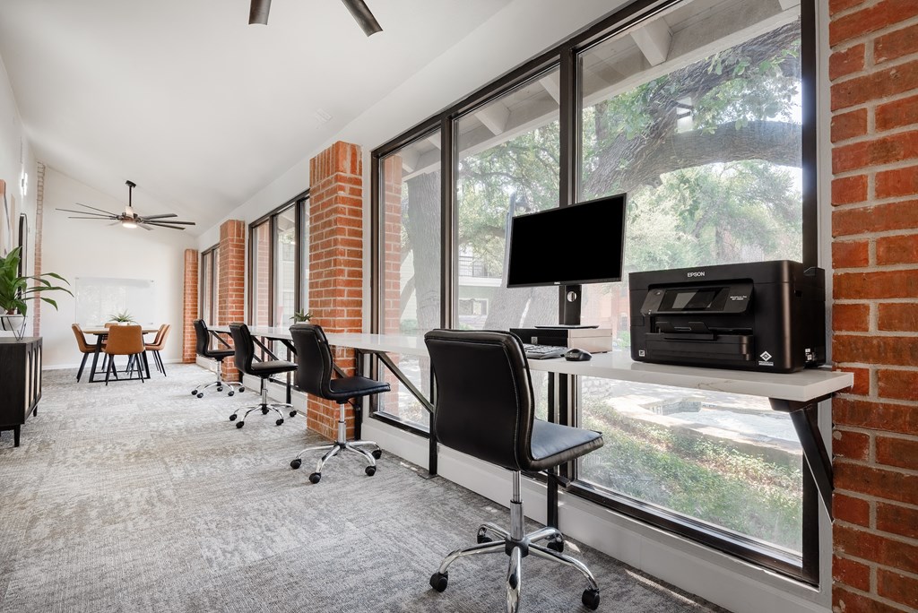 an office with a brick wall and a desk with a computer on it