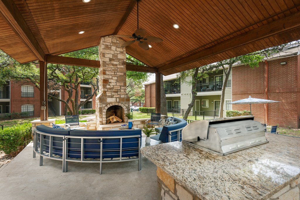 a covered patio with a fireplace and a grill