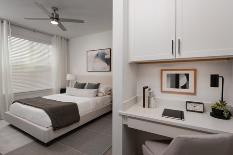 a bedroom with a white bed and a desk and a window