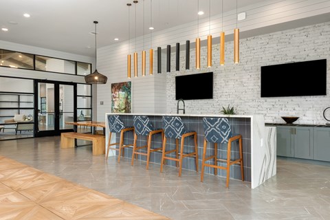 a large kitchen with a long bar with chairs and a white brick wall