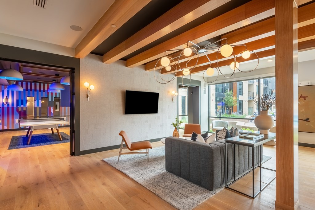 A modern living room with a grey sofa and a wooden floor.