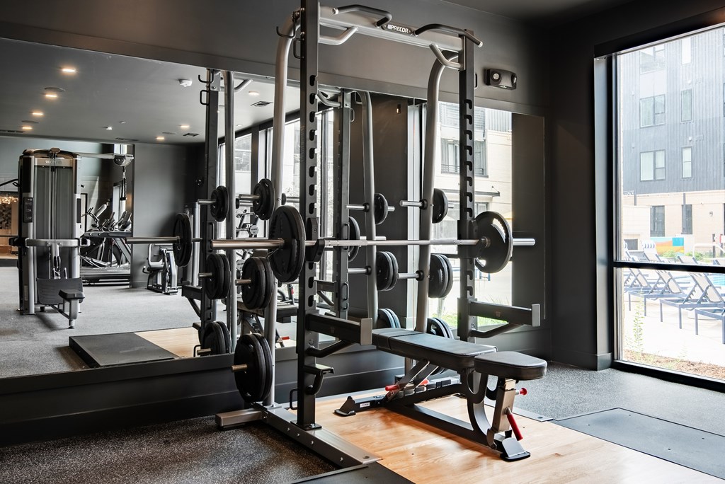A gym with a variety of equipment including a squat rack and bench.