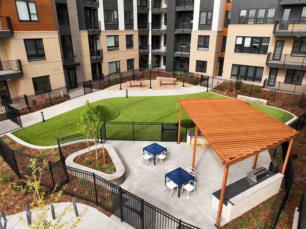 A patio with a table and chairs is surrounded by a black fence.