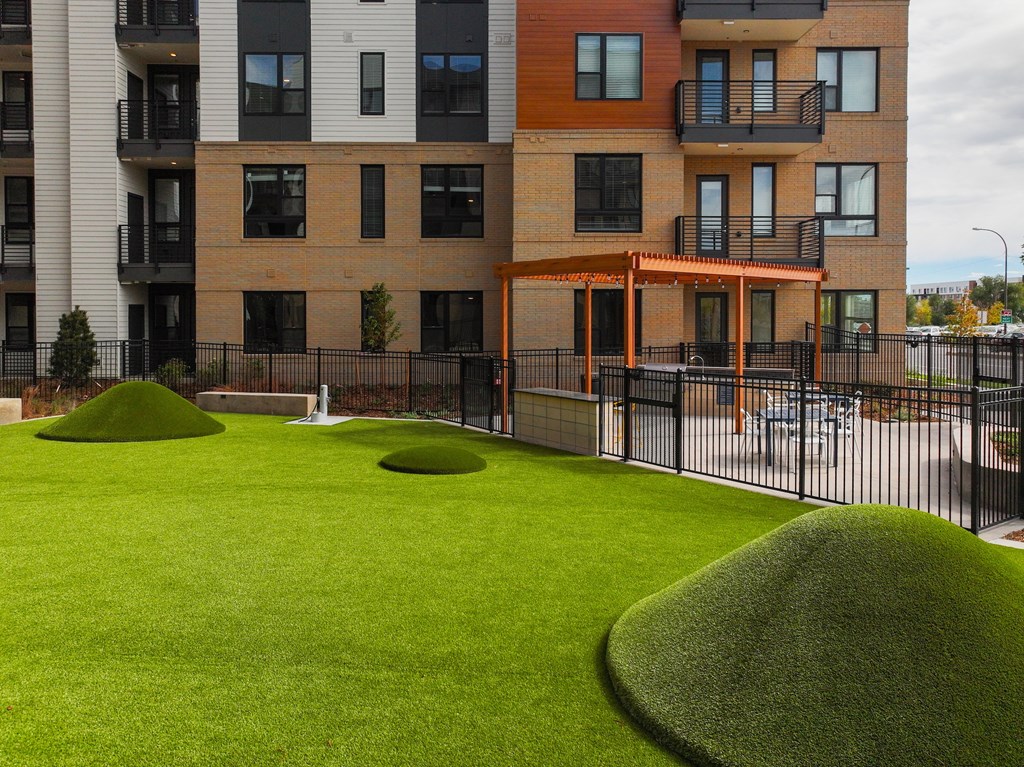A grassy area in front of a building with a black fence.