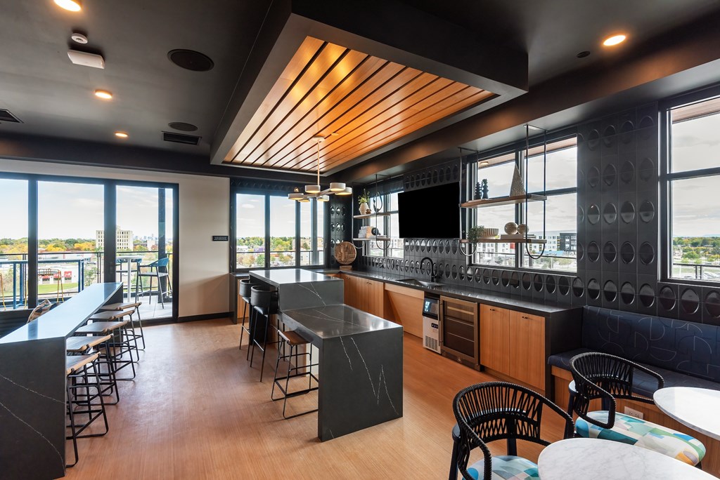 A modern kitchen and dining area with a wooden ceiling and black countertops.