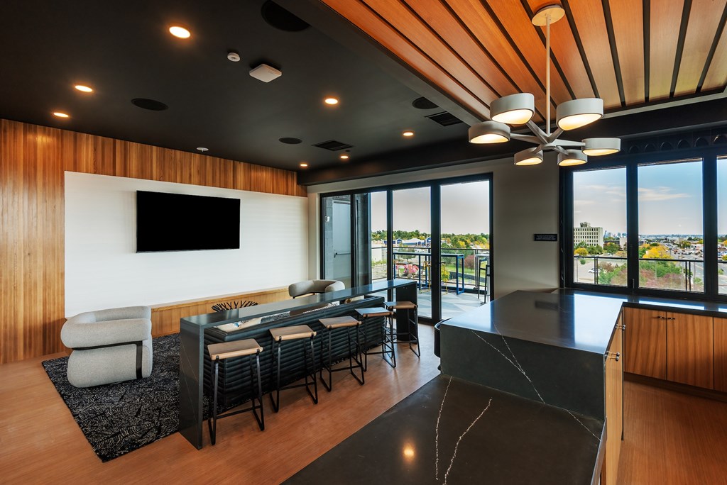 A modern living room with a black sofa and a television on the wall.
