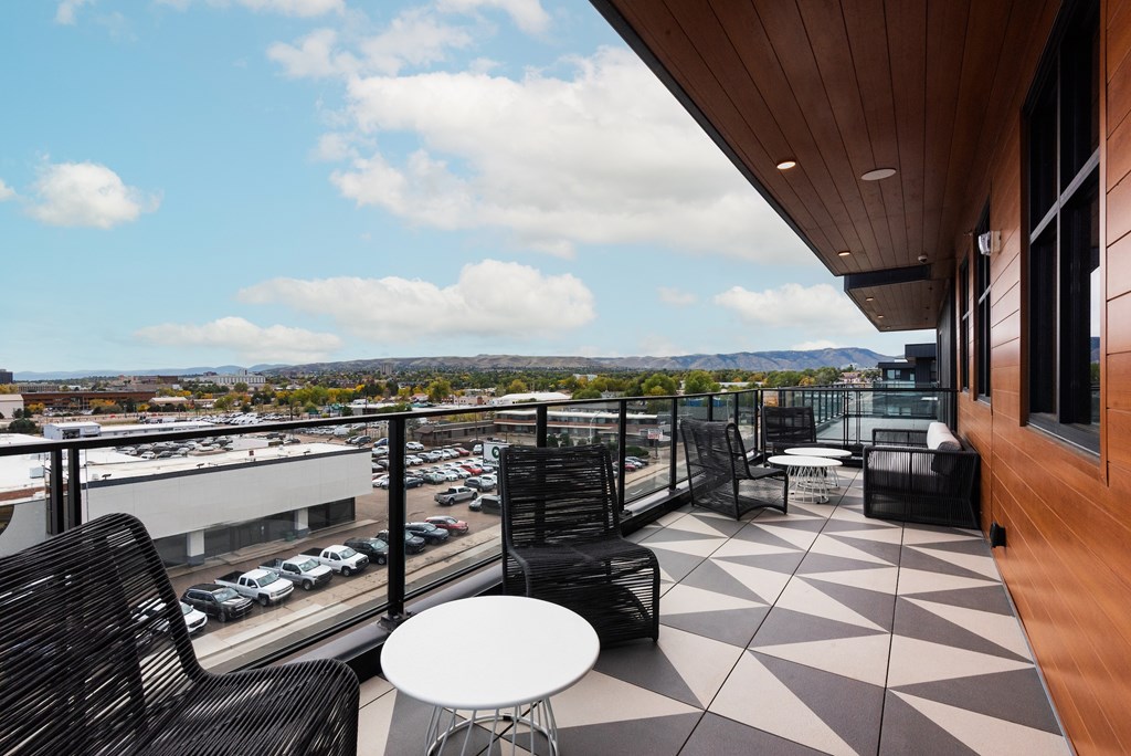 A patio with a table and chairs overlooking a parking lot.