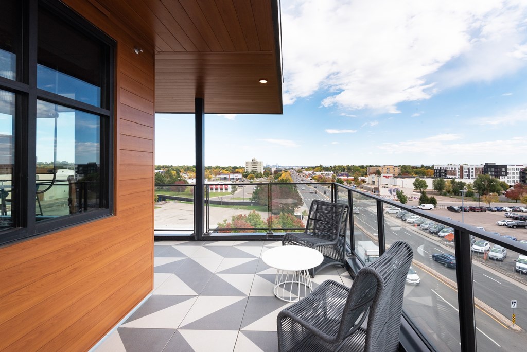 A balcony with a table and chairs overlooking a street.