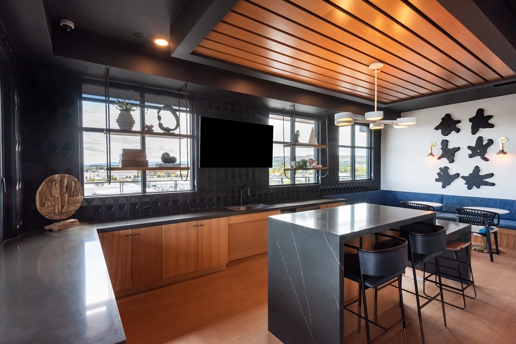A modern kitchen with a wooden ceiling and black countertops.