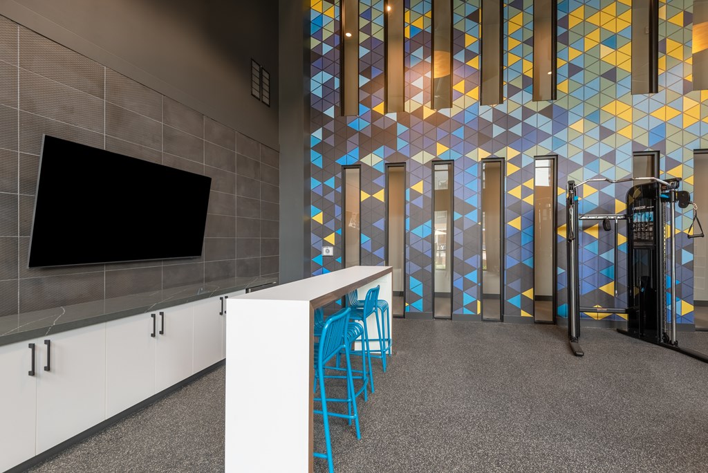 A room with a white counter and blue chairs.