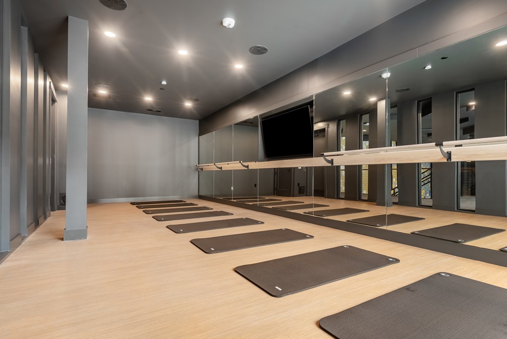 A yoga studio with mats on the floor and mirrors on the wall.