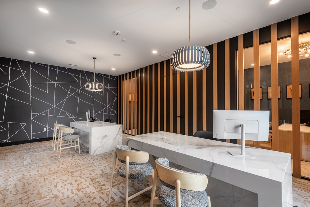 A modern office space with a white marble desk and wooden chairs.