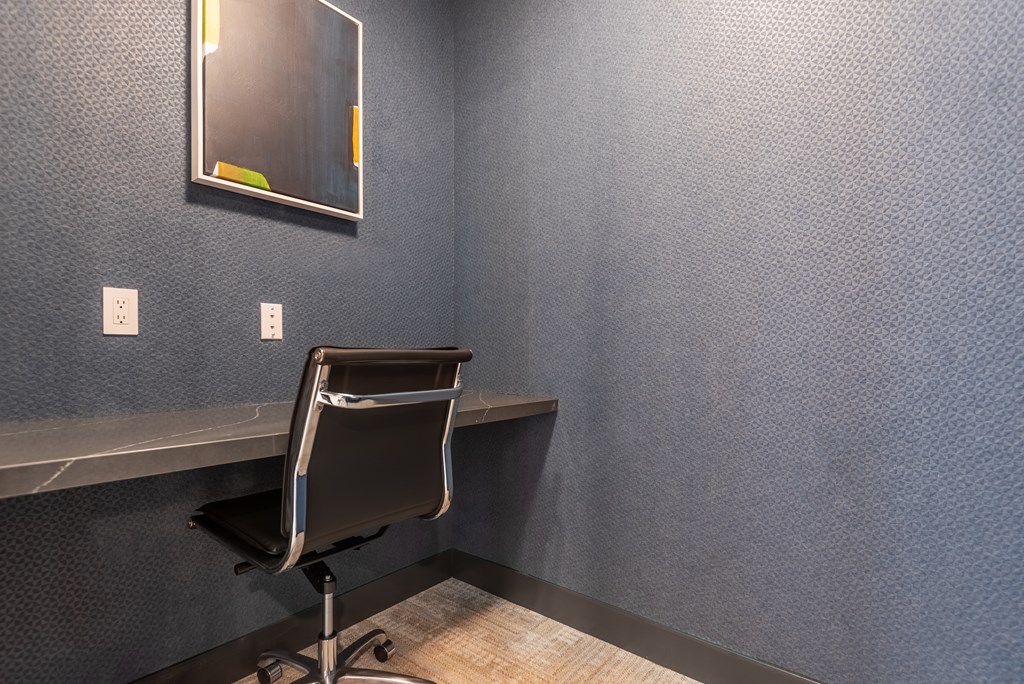 A black chair is in front of a wall with a mirror and two switches.