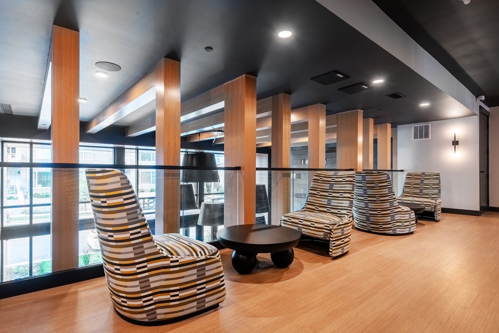A row of striped chairs are lined up in a room with wooden floors and a large window.