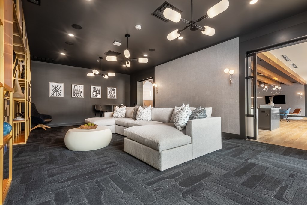 A modern living room with a grey carpet and a white sofa.