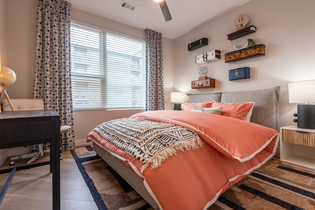 A bedroom with a bed covered in an orange blanket.