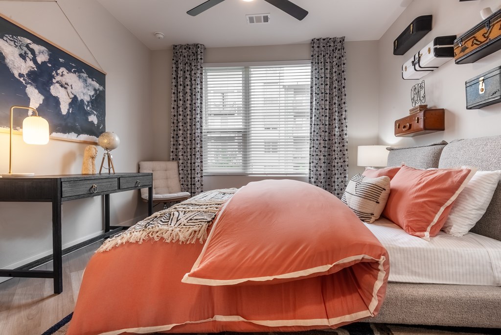 A bedroom with a bed covered in an orange duvet.