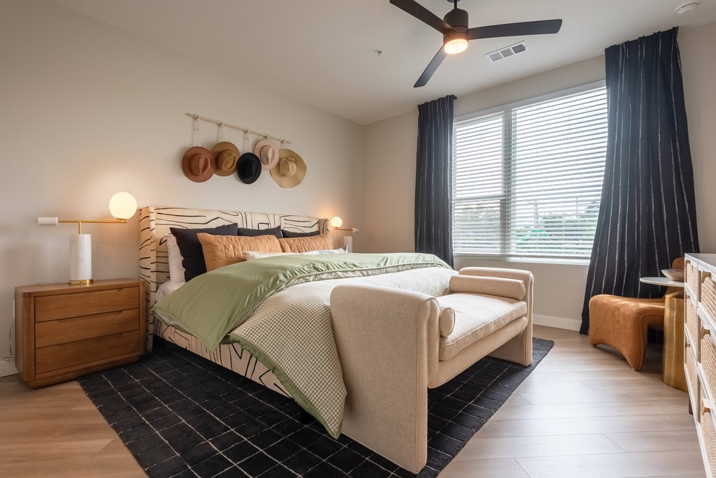 A bedroom with a bed, a nightstand, and a ceiling fan.
