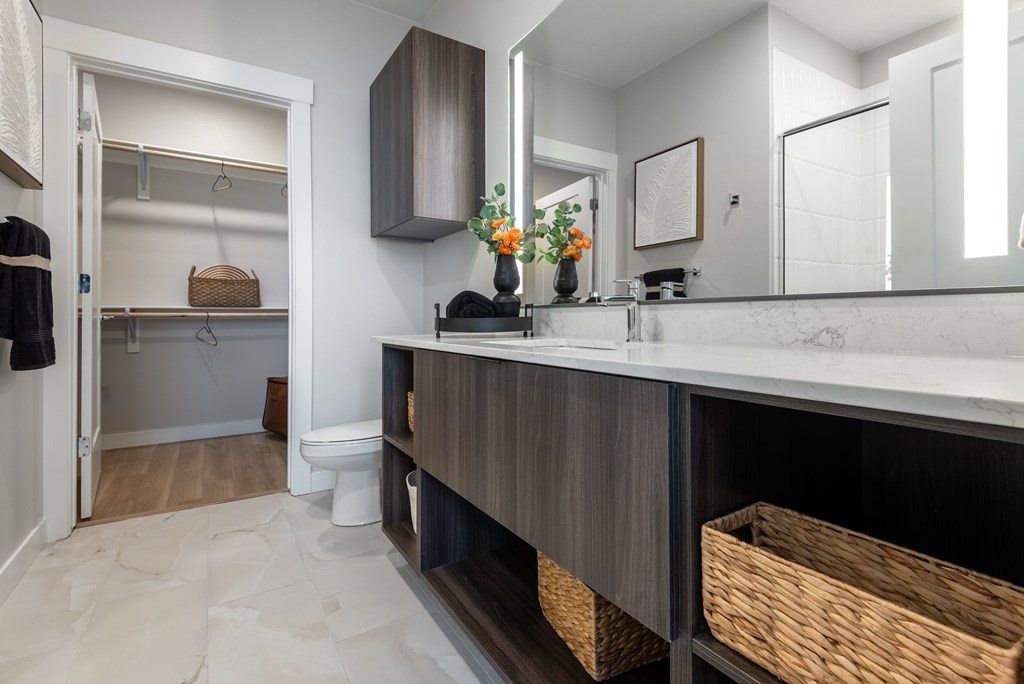 A bathroom with a white counter top and a mirror above it.
